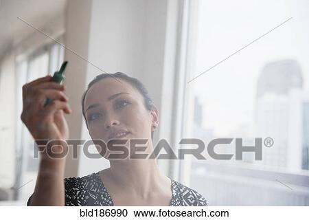 Stock Image - Businesswoman writing on glass wall. Fotosearch