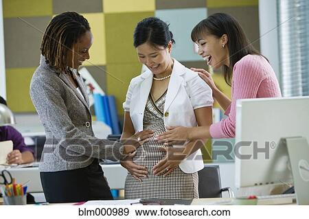 Stock Photo - Businesswomen admiring pregnant co-workerÆs stomach. Fotosearch
