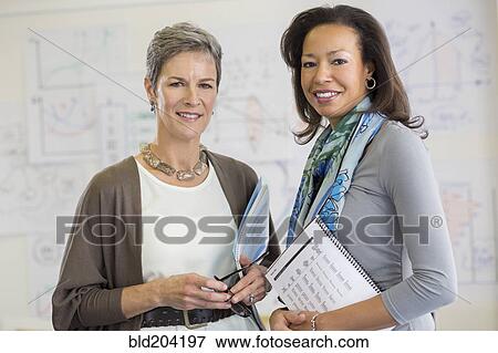 Businesswomen smiling in office View Large Photo Image Stock Photo - Businesswomen smiling in office. Fotosearch