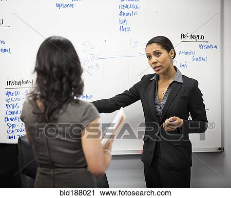Stock Image - Businesswomen talking in office. Fotosearch