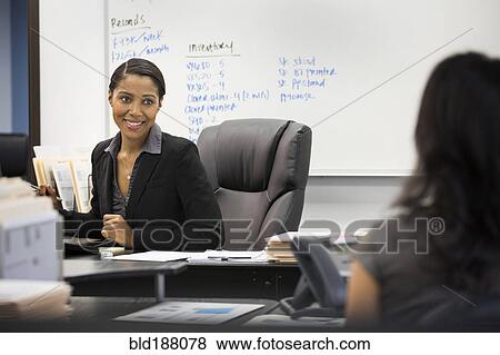 Stock Photo - Businesswomen talking in office. Fotosearch