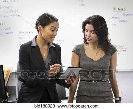 Businesswomen talking with notepad in office View Large Photo Image Stock Image - Businesswomen talking with notepad in office. Fotosearch