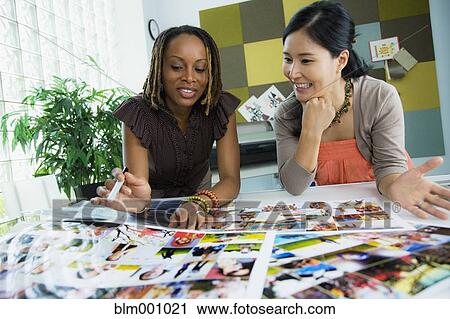 Stock Image - Businesswomen working together in office. Fotosearch