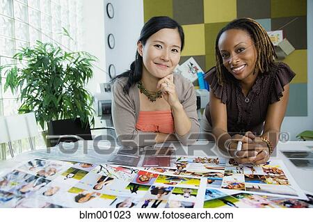 Stock Image - Businesswomen working together in office. Fotosearch