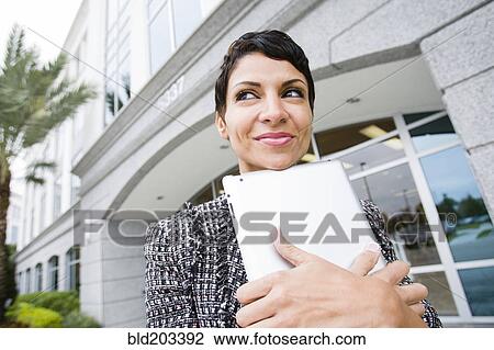 Stock Image - Cape Verdean businesswoman holding tablet computer outdoors. Fotosearch