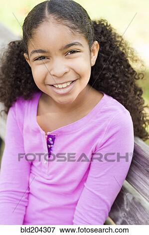 Stock Photo - Cape Verdean girl smiling on park bench. Fotosearch