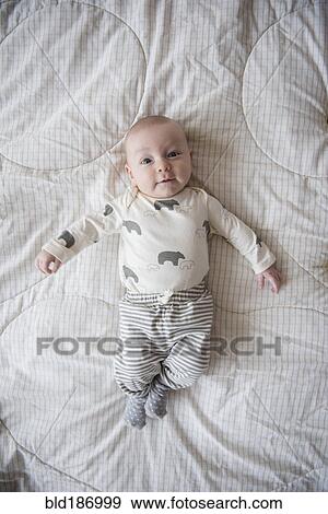 Caucasian baby laying on bed View Large Photo Image Stock Photo - Caucasian baby laying on bed. Fotosearch