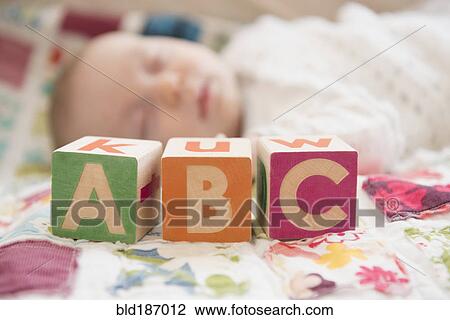 Stock Image - Caucasian baby napping near wooden blocks. Fotosearch