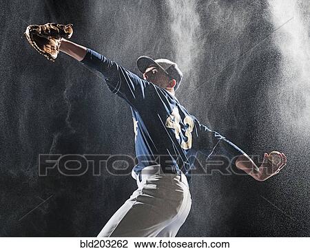 Stock Image - Caucasian baseball player pitching in rain. Fotosearch