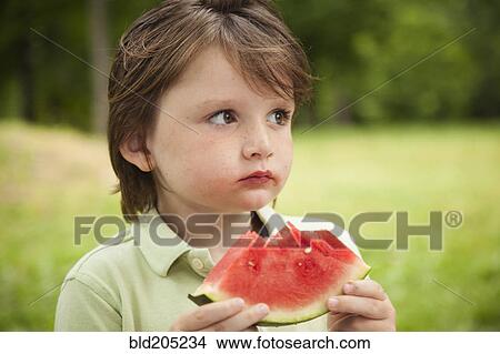 Caucasian boy eating watermelon outdoors View Large Photo Image Picture - Caucasian boy eating watermelon outdoors. Fotosearch