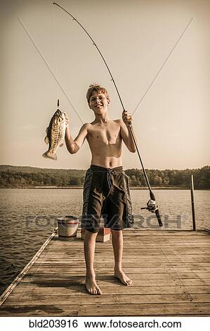 Stock Photograph - Caucasian boy holding freshly caught fish. Fotosearch