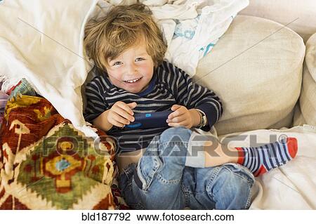 Stock Image - Caucasian boy laying on sofa. Fotosearch