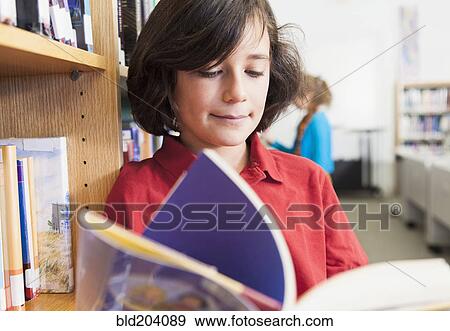 Stock Photo - Caucasian boy reading book in library. Fotosearch