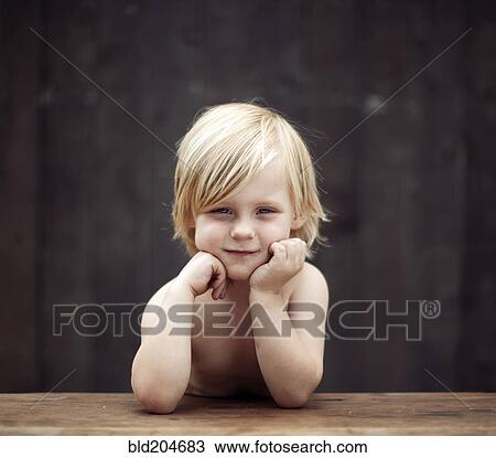 Stock Image - Caucasian boy sitting at table outdoors. Fotosearch