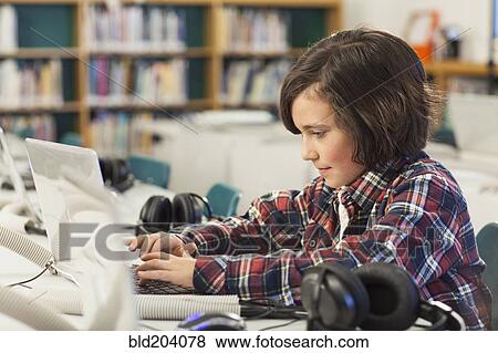 Stock Photo - Caucasian boy using laptop in library. Fotosearch