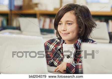 Stock Photo - Caucasian boy using laptop in library. Fotosearch