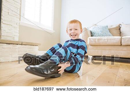 Caucasian boy wearing shoes of father in living room View Large Photo Image Stock Photo - Caucasian boy wearing shoes of father in living room. Fotosearch