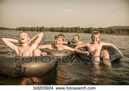 Picture - Caucasian boys with inner tubes in water. Fotosearch