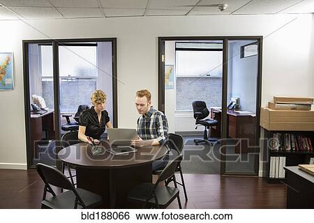 Stock Photograph - Caucasian business people using laptop in office. Fotosearch