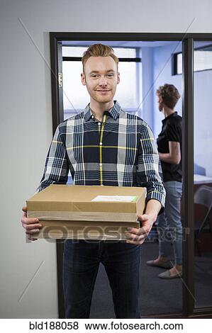 Caucasian businessman carrying packages in office View Large Photo Image Stock Photo - Caucasian businessman carrying packages in office. Fotosearch