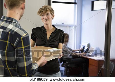 Stock Photo - Caucasian businessman delivering packages in office. Fotosearch