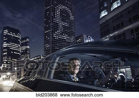 Stock Photo - Caucasian businessman driving on city street. Fotosearch