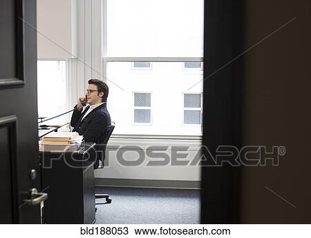 Stock Image - Caucasian businessman talking on telephone in office. Fotosearch