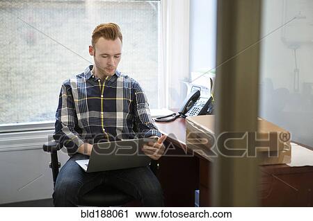 Stock Image - Caucasian businessman using laptop in office. Fotosearch