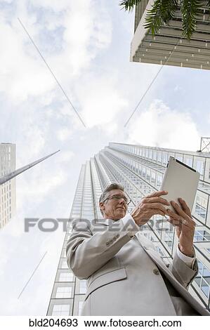 Caucasian businessman with tablet computer on city street View Large Photo Image Stock Image - Caucasian businessman with tablet computer on city street. Fotosearch