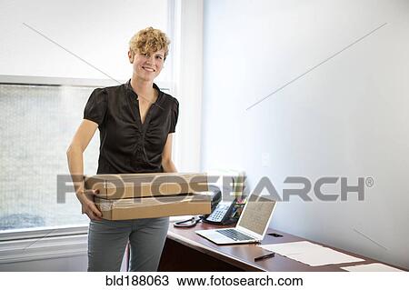 Caucasian businesswoman holding package in office View Large Photo Image Stock Image - Caucasian businesswoman holding package in office. Fotosearch