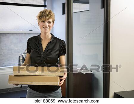 Stock Photo - Caucasian businesswoman holding packages in office. Fotosearch