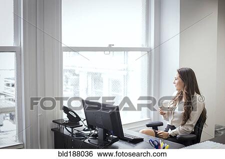 Stock Photograph - Caucasian businesswoman looking out office window. Fotosearch