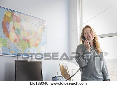Stock Image - Caucasian businesswoman talking on telephone in office. Fotosearch