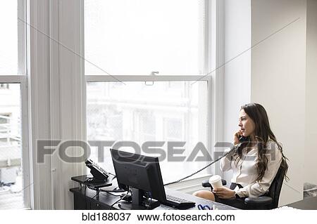 Stock Photo - Caucasian businesswoman talking on telephone in office. Fotosearch
