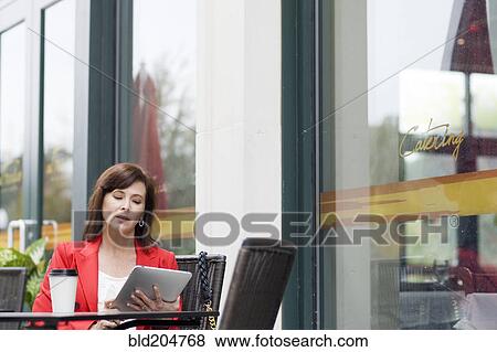 Stock Photo - Caucasian businesswoman using tablet at cafe. Fotosearch