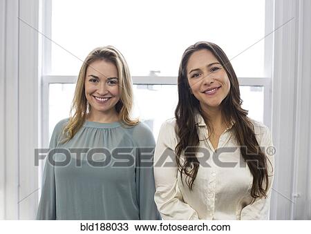 Stock Image - Caucasian businesswomen smiling near window. Fotosearch