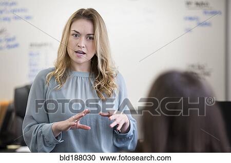 Stock Image - Caucasian businesswomen talking in office. Fotosearch