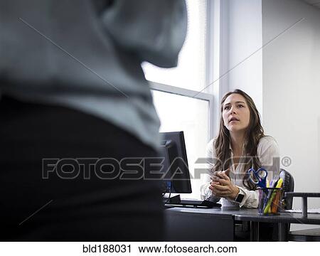 Stock Image - Caucasian businesswomen talking in office. Fotosearch