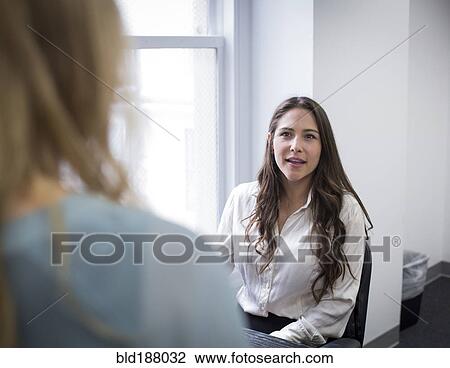 Stock Image - Caucasian businesswomen talking in office. Fotosearch