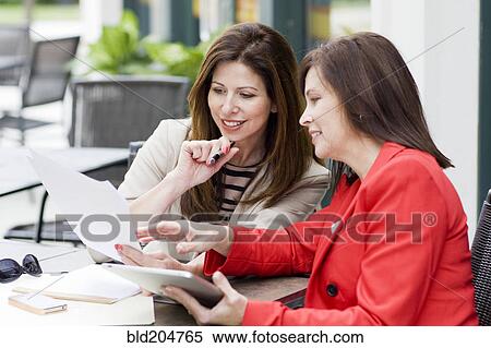 Stock Photography - Caucasian businesswomen working in cafe. Fotosearch