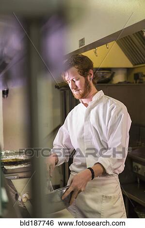 Stock Photograph - Caucasian chef reading orders in restaurant kitchen. Fotosearch