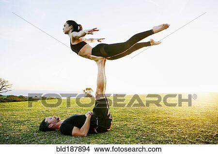 Picture - Caucasian couple doing acro yoga in park. Fotosearch