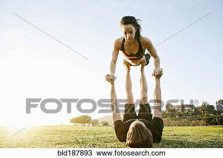 Stock Image - Caucasian couple doing acro yoga in park. Fotosearch