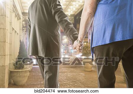 Picture - Caucasian couple holding hands outdoors. Fotosearch
