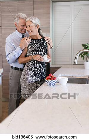 Stock Photography - Caucasian couple hugging in kitchen. Fotosearch