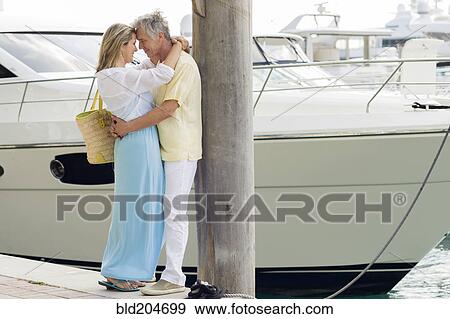 Stock Photo - Caucasian couple hugging on dock. Fotosearch