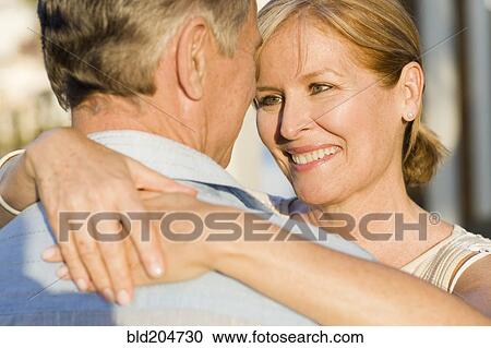 Stock Image - Caucasian couple hugging outdoors. Fotosearch