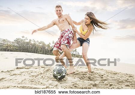 Stock Photography - Caucasian couple playing on beach. Fotosearch