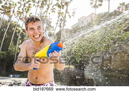 Stock Photo - Caucasian couple playing with squirt guns on beach. Fotosearch