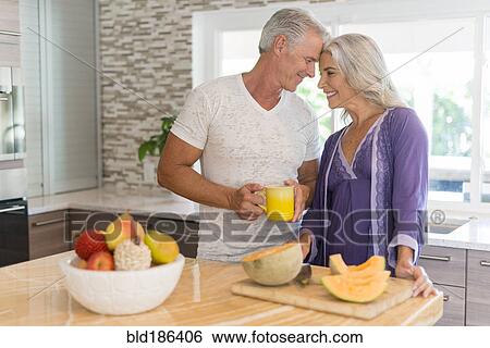 Stock Photograph - Caucasian couple touching foreheads in kitchen. Fotosearch